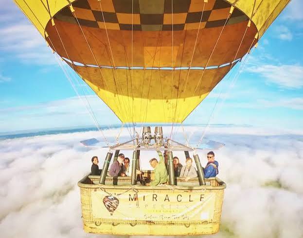 A colorful hot air balloon soaring over the Serengeti plains at sunrise, offering a bird's-eye view of the wildlife below